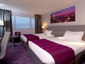 a hotel room with two beds and a table at Mercure Paris 19 Philharmonie La Villette in Paris