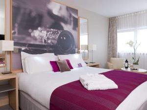 - une chambre dotée d'un grand lit avec des oreillers violets et blancs dans l'établissement Mercure Paris 19 Philharmonie La Villette, à Paris