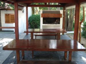 2 bancs en bois sur une terrasse avec une cheminée dans l'établissement El Agora, à Villa General Belgrano