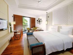 een slaapkamer met een groot bed en een woonkamer bij Pullman Danang Beach Resort in Da Nang