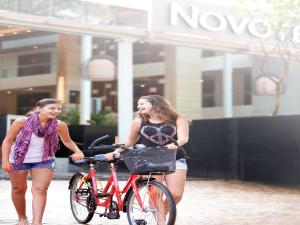 two women walking a bike on a street at Novotel Goa Candolim in Candolim