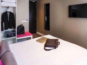 a bedroom with a bed with a laptop and a suit on a rack at ibis Styles Amsterdam Amstel in Amsterdam