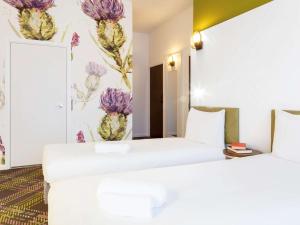 2 camas en una habitación de hotel con flores en la pared en ibis Styles Edinburgh St Andrew Square, en Edimburgo