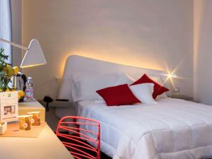 sypialnia z białym łóżkiem z czerwonymi poduszkami w obiekcie Ibis Styles Palermo President w mieście Palermo