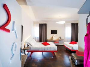 una camera d'albergo con due letti con cuscini rossi di Ibis Styles Palermo President a Palermo