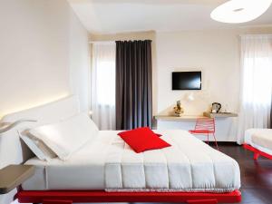 ein Hotelzimmer mit einem weißen Bett und einem roten Kissen in der Unterkunft Ibis Styles Palermo President in Palermo