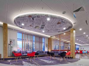 a waiting room with red chairs and a large ceiling at ibis Ankara Airport Hotel in Ankara
