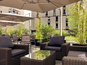 une terrasse avec des chaises, des tables et un parasol dans l'établissement Mercure Clermont Ferrand centre Jaude, à Clermont-Ferrand