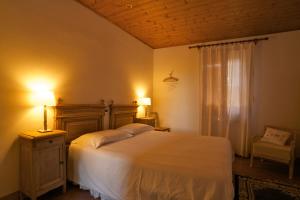 una camera con un grande letto bianco e due lampade di B&B Casa Volton a Bevazzana