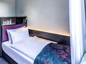 1 dormitorio con 1 cama con cabecero púrpura en Mercure Frankfurt City Messe, en Frankfurt