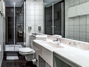 een badkamer met een wastafel, een toilet en een spiegel bij Mercure Frankfurt City Messe in Frankfurt am Main