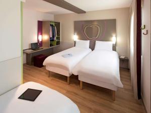 リェイダにあるHotel Ibis Styles Lleida Torrefarreraのベッド2台とデスクが備わるホテルルームです。