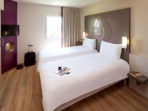 um quarto de hotel com duas camas e uma mala em Hotel Ibis Styles Lleida Torrefarrera em Lleida