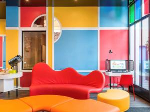 クルブヴォアにあるイビス スタイルズ パリ ラ デファンス クルブヴォアの赤いソファとカラフルな壁のリビングルーム