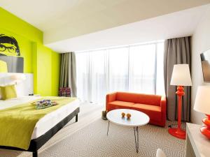a hotel room with a bed and a couch and a table at Ibis Styles Wroclaw Centrum in Wrocław