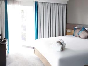 a bedroom with a white bed with blue and white pillows at Novotel London Wembley in London