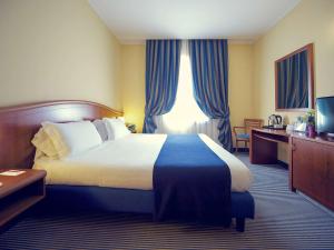 a hotel room with a large bed with blue curtains at Mercure Genova San Biagio in Genoa