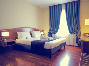 een slaapkamer met een groot bed met blauwe gordijnen bij Mercure Genova San Biagio in Genua