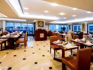 a restaurant with wooden tables and chairs and windows at Grand Mercure Majlis Residences in Abu Dhabi
