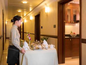 a woman standing next to a table in a room at Grand Mercure Majlis Residences in Abu Dhabi