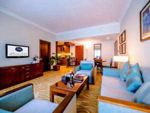 a living room with blue couches and a table at Grand Mercure Majlis Residences in Abu Dhabi