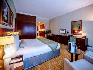 a hotel room with a large bed and a couch at Grand Mercure Majlis Residences in Abu Dhabi