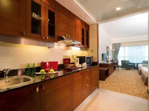 a kitchen with a sink and a living room at Grand Mercure Majlis Residences in Abu Dhabi