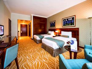 a hotel room with two beds and a television at Grand Mercure Majlis Residences in Abu Dhabi