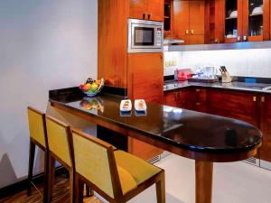 a kitchen with a table with chairs and a microwave at Grand Mercure Majlis Residences in Abu Dhabi