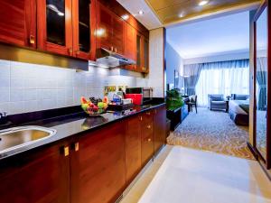 a kitchen with a sink and a living room at Grand Mercure Majlis Residences in Abu Dhabi