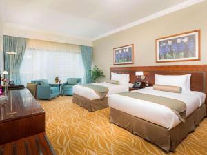 a hotel room with two beds and a couch at Grand Mercure Majlis Residences in Abu Dhabi