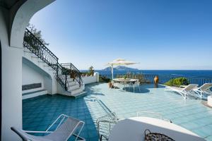 een terras met stoelen en een tafel en de oceaan bij VILLA SOLEIL in Massa Lubrense