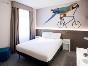 a hotel room with a bed and a bird on a bike on the wall at Heeton Concept Hotel - Kensington London in London