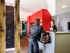 un homme debout devant un comptoir devant une femme dans l'établissement hotelF1 Grenoble Université, à Gières