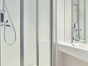 una ducha con una puerta de cristal junto a un lavabo en hotelF1 Limoges, en Limoges