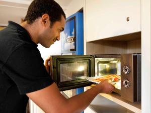 a man is putting a pizza in an oven at hotelF1 Pontarlier in Pontarlier