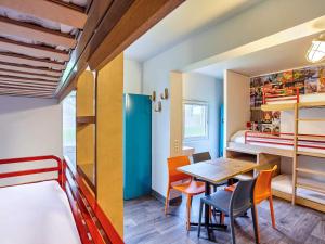 サン・ドニにあるhotelF1 Paris Saint Denis Stadeのテーブル、椅子、二段ベッドが備わる小さな客室です。