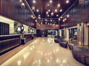 a large lobby with couches and lights in a building at Mercure Bali Legian in Legian