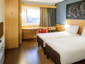 a hotel room with a bed, chair, and nightstand at ibis Imperatriz in Imperatriz
