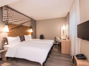 ein Hotelzimmer mit einem großen Bett und einem TV in der Unterkunft Ibis Muenchen City Ost in München