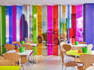 巴拉奈里奧－坎布里烏的住宿－Ibis Styles Balneário Camboriú - 1 Quadra do Mar，餐厅设有桌椅和色彩缤纷的墙壁