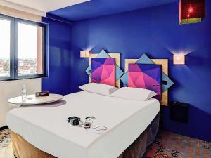 ein Schlafzimmer mit einem großen weißen Bett mit blauen Wänden in der Unterkunft ibis styles Albi Centre Le Theatro in Albi