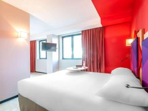 a bedroom with a large white bed with a red wall at ibis styles Albi Centre Le Theatro in Albi