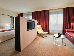 a hotel room with a television and a bed and a table at Pullman Kinshasa Grand Hotel in Kinshasa