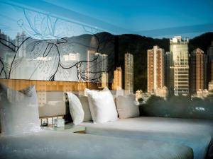 a bed with white pillows and a mural of a city at The Park Lane Hong Kong, a Pullman Hotel in Hong Kong