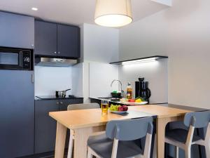 a kitchen with a wooden table and chairs at Aparthotel Adagio access München City Olympiapark in Munich