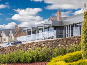 a building with glass windows and a stone wall at Mercure Goulburn in Goulburn