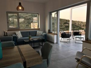 a living room with a couch and tables and windows at Avgi Villa in Agios Nikolaos