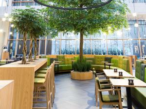 a restaurant with tables and chairs and trees at Novotel Amsterdam Schiphol Airport in Hoofddorp