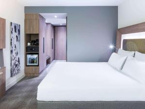 a bedroom with a large white bed and a tv at Novotel Amsterdam Schiphol Airport in Hoofddorp